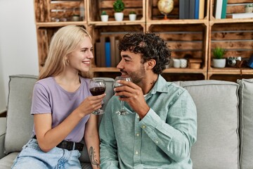 Young couple smiling happy toasting with red wine glass at home.