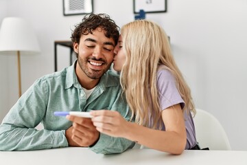 Fototapeta premium Young couple smiling happy looking pregnant test result at home.