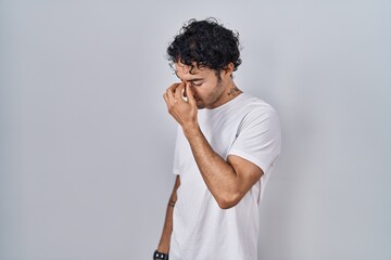 Hispanic man standing over isolated background tired rubbing nose and eyes feeling fatigue and headache. stress and frustration concept.