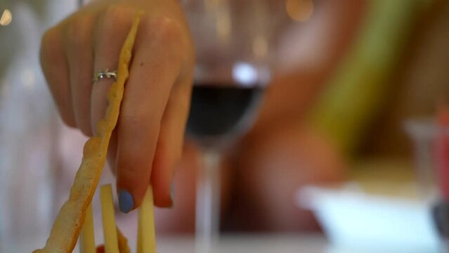 Charcuterie board and wine. Young woman in luxury all-inclusive resort room. Caribbean tourism theme. Extreme close up, tilt up to reveal young woman.
