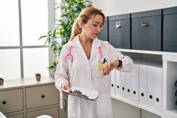 Hispanic doctor woman looking at the watch relaxed with serious expression on face. simple and...