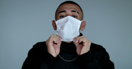Hispanic latino young man adjusting face mask