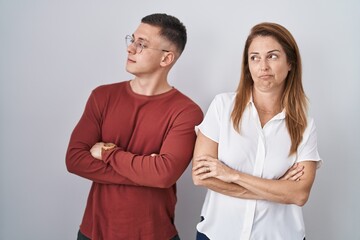 Mother and son standing together over isolated background looking to the side with arms crossed convinced and confident