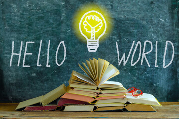 stack of books in front of a blackboard, drawing of a lightbulb and slogan hello world,knowledge,...