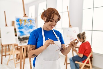 Two artist student women smiling happy painting at art school. Girl holding palette and paintbrush.