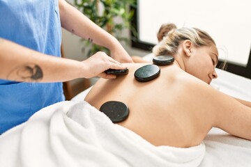 Obraz na płótnie Canvas Woman couple having back treatment using hot black stones at beauty center