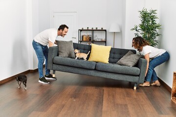 Middle age hispanic couple holding sofa at home.