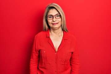 Middle age hispanic woman wearing casual clothes and glasses looking positive and happy standing and smiling with a confident smile showing teeth