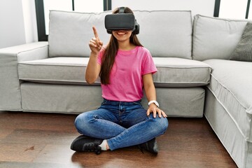 Young latin woman playing video game using vr goggles at home