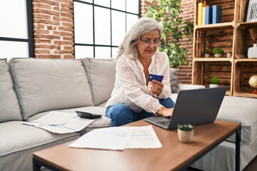 Middle age woman using laptop and credit card at home