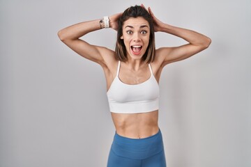 Fototapeta na wymiar Hispanic woman wearing sportswear over isolated background crazy and scared with hands on head, afraid and surprised of shock with open mouth