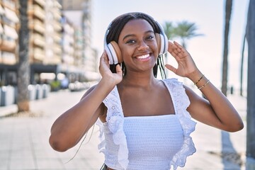 Young african american girl smiling happy listening to music at the promenade.