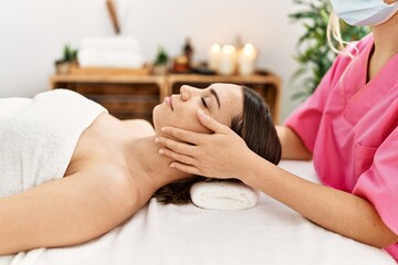 Young hispanic woman smiling confident having massage at beauty center.