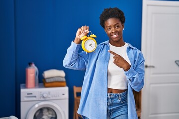 African american woman waiting for laundry smiling happy pointing with hand and finger