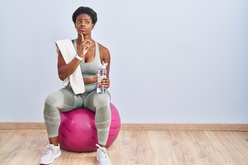African american woman wearing sportswear sitting on pilates ball thinking concentrated about doubt...