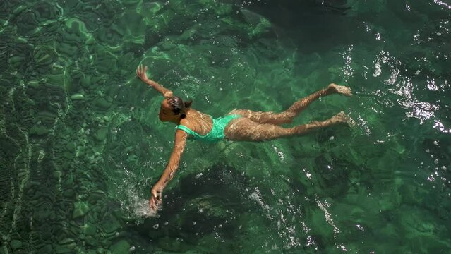 slow motion top view of sexy stunning woman with nise buttocks in green swimsuit floating in clear turquoise water of mediterranean sea. vacation and wellness, Summer Season Fethiye, Turkey