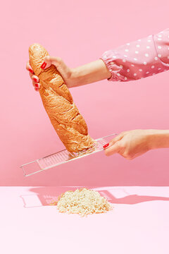 Naklejki Female hands grating bread, baguette to make breadcrumb for meat isolated over pink background