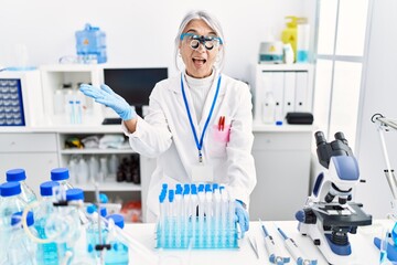 Fototapeta premium Middle age grey-haired woman wearing scientist uniform celebrating achievement with happy smile and winner expression with raised hand