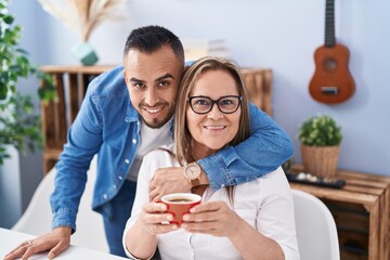 Man and woman mother and son drinking coffee hugging at home