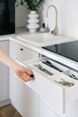 Woman open white cutlery drawer in a modern kitchen