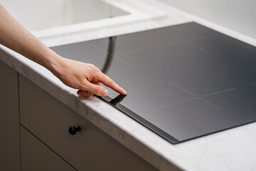 Woman press button on control panel at modern induction stove