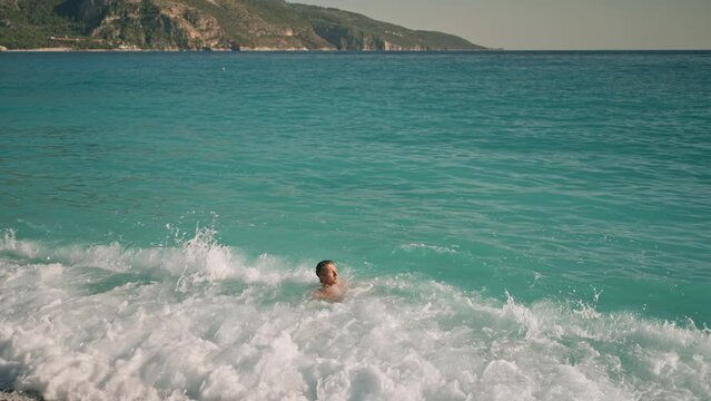 relaxed handsome athletic man in blue swim trunks enjoying by lying on turquoise water of mediterranean sea in Oludeniz Beach in Aegean Sea after swimming and sunbathing. summertime wibe