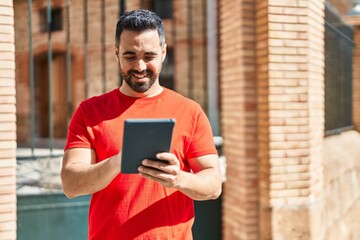 Young hispanic man smiling confident using touchpad at street