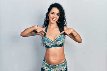 Fototapeta premium Young woman wearing bindi and traditional belly dance clothes looking confident with smile on face, pointing oneself with fingers proud and happy.