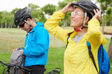 Naklejka premium Cyclist in sunglasses and protective helmet taking water bottle out of backpack