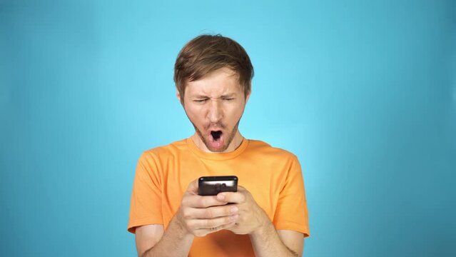 Confused young man with disgust look at smartphone screen in surprise. Grimacing guy reading a text message.