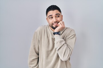 Young handsome man standing over isolated background looking stressed and nervous with hands on mouth biting nails. anxiety problem.