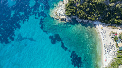 View from above, aerial view of an emerald and transparent Mediterranean sea with a white beach full of colored beach umbrellas and tourists who relax and swim