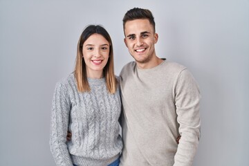 Young hispanic couple standing over white background with a happy and cool smile on face. lucky...