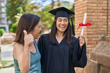 Two women mother and graduated daughter doing ok gesture at street