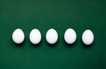 Five eggs lie on a dark green background - 519196499