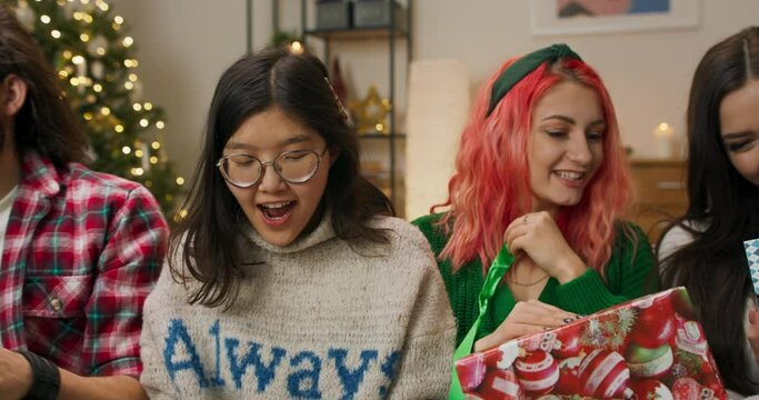 During the Christmas party, friends sat on the couch in the living room and it was time to receive gifts. Girls open their presents and are delighted with what they received. Boys discuss the book.