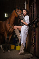 Young beautiful girl with the horse in the stable.