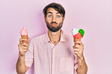 Young hispanic man holding ice cream looking at the camera blowing a kiss being lovely and sexy....
