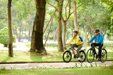 Couple enjoying bicycle ride in city park on sunny Sunday morning