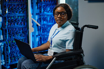 Portrait of African female IT engineer with disability sitting in wheelchair and looking at camera...