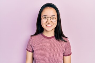 Fototapeta premium Young chinese girl wearing casual clothes and glasses with a happy and cool smile on face. lucky person.