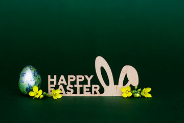 Wooden inscription Happy Easter stylized bunny ears on a dark green background - 519198417