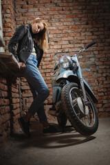 Fototapeta na wymiar Young beautiful girl in the leather jacket is posing near the motorbike concept.