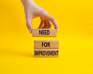 Need for Improvement symbol. Wooden blocks with words Need for Improvement. Beautiful yellow background. Businessman hand. Business and Need for Improvement concept. Copy space.