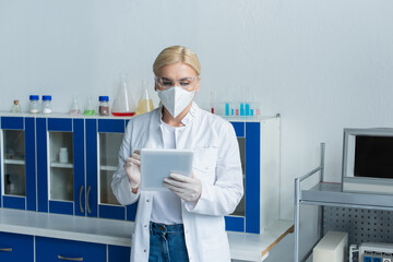 Fototapeta premium Scientist in protective mask using digital tablet in lab.