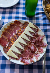 A delicious tapas board of pork raw meats and sheep cheese with a traditional asturian bottle of cider on the side