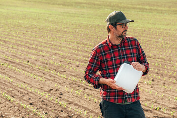 Corn crop protection concept, male farmer agronomist holding jerry can container canister with...