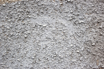 The texture of the concrete wall part with a small crumb of stone. Grey Textured cement wall background with a stone chip. Concrete wall of the building with stones of different sizes.