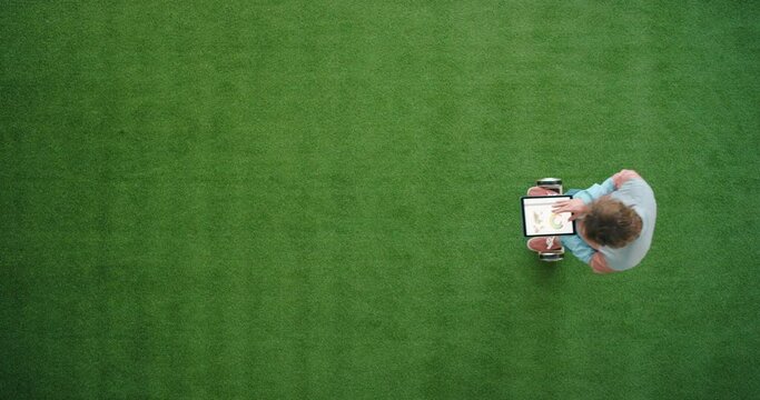 Modern business man riding a hoverboard from above while working on a digital tablet in a futuristic and trendy startup company. Aerial view of a stylish male entrepreneur using a wireless gadget