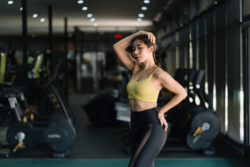 Fototapeta na wymiar Beautiful Asian woman in a sporty workout clothes shows off her perfect figure to relieve the fatigue of gym workouts.